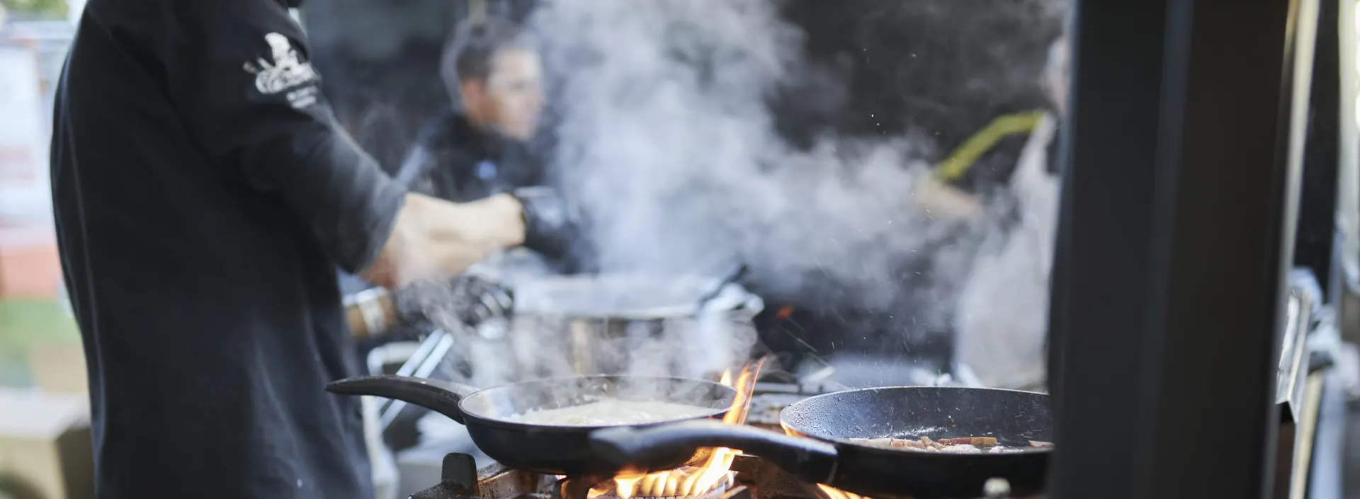 Nagykonyhai főzés gázégőkön: serpenyők, láng és felszálló gőz